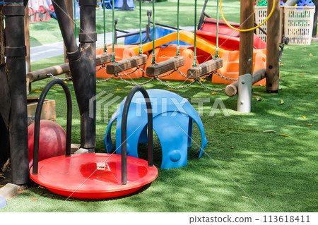 Playground in the park with blue and red seats and swings. Playground in the park with blue and red seats and swings. 113618411