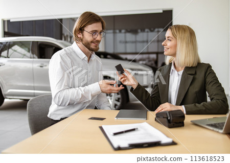 Happy Caucasian young man sitting at table and receives keys of SUV car. 113618523