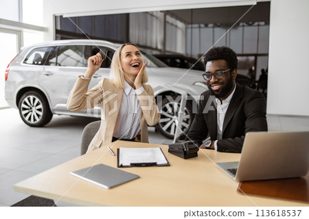 Happy Caucasian young woman sitting at table and receives keys of SUV car. 113618537