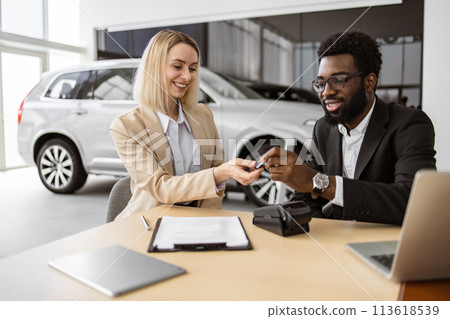 Happy Caucasian young woman sitting at table and receives keys of SUV car. Happy Caucasian young woman sitting at table and receives keys of SUV car. 113618539