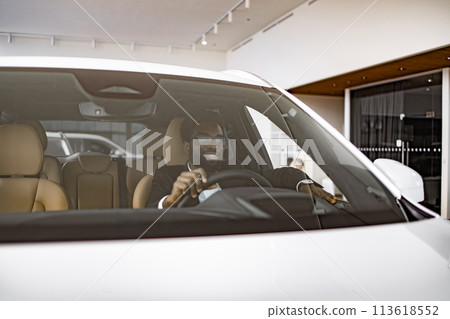 Calm African man customer buyer client in suit holding hands on steering wheel. 113618552