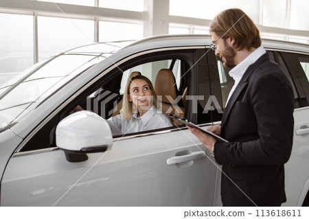 Satisfied happy Caucasian female client customer sitting at steering wheel . 113618611