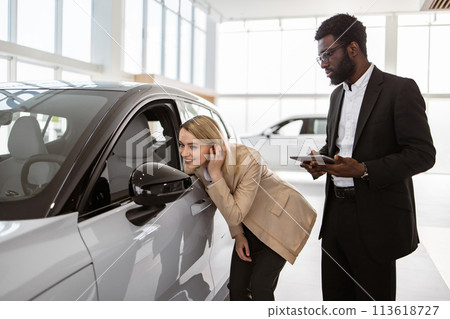 Successful businesswoman in car showroom sale of vehicles to customers. 113618727