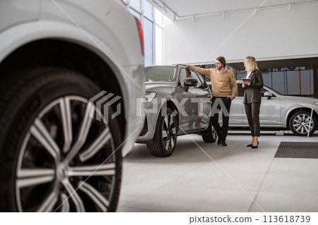 Successful businessman in car showroom, sale of vehicles to customers. Successful businessman in car showroom, sale of vehicles to customers. 113618739