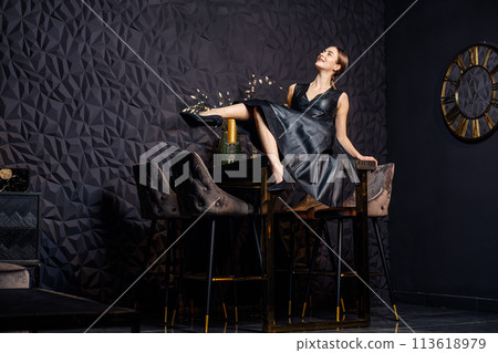 Girl having fun and swings her legs at home sitting on bar table 113618979