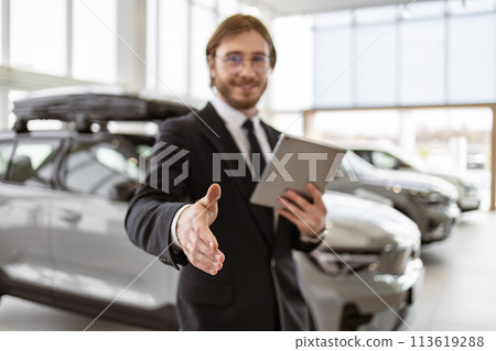 Bearded manager shaking hand with buyer on background of rows of crossovers. 113619288