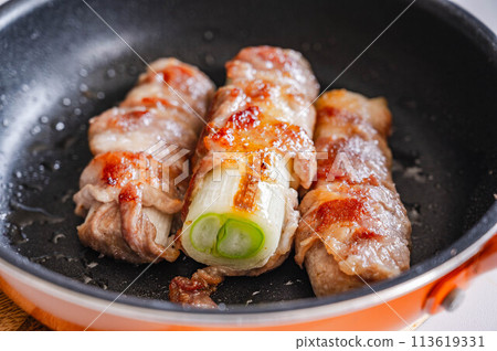 Pork wrapped in white onion cooked in a frying pan Pork wrapped in white onion cooked in a frying pan 113619331