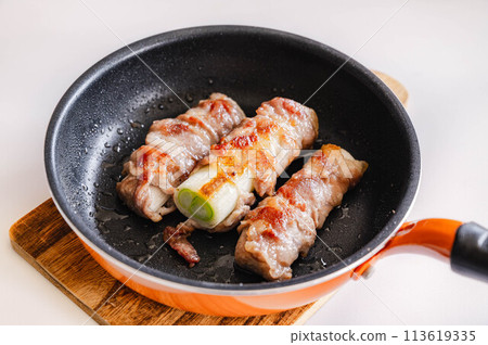 Pork wrapped in white onion cooked in a frying pan 113619335