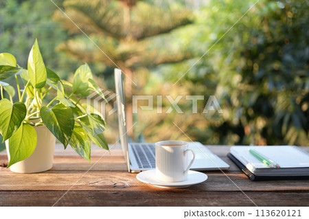 Laptop side view and coffee cup with notebooks on white table outdoor 113620121
