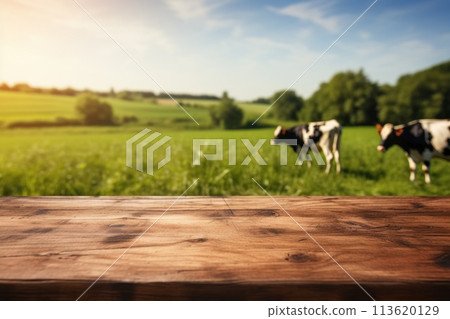 Empty wooden tabletop and blurred rural background of cows on green field and meadow with grass. Space for design your product. 113620129