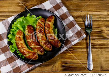 Tasty grilled sausages on a wooden table. Top view 113620504
