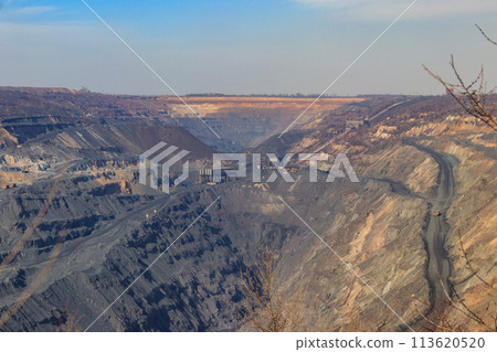 Huge iron ore quarry with working dump trucks and excavators 113620520