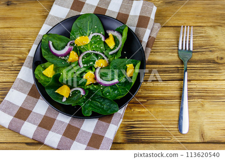 Tasty salad with spinach, orange, red onion and sesame seeds on wooden table. Top view. Healthy food or vegetarian concept 113620540
