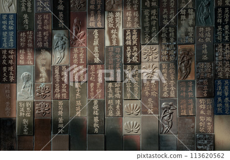 Chinese lettering teachings and Carved buddha images into a slab of colored tiles on temple wall. Chinese lettering teachings and Carved buddha images into a slab of colored tiles on temple wall. 113620562