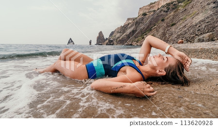 Woman summer travel sea. Happy tourist in blue bikini enjoy taking picture outdoors for memories. Woman traveler posing on the beach surrounded by volcanic mountains, sharing travel adventure journey Woman summer travel sea. Happy tourist in blue bikini enjoy taking picture outdoors for memories. Woman traveler posing on the beach surrounded by volcanic mountains, sharing travel adventure journey 113620928