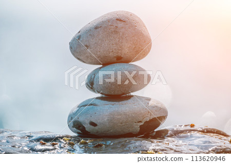 Balanced rock pyramid on sea pebbles beach, sunny day and clear sky at sunset. Golden sea bokeh on background. Selective focus, zen stones on sea beach, meditation, spa, harmony, calm, balance concept 113620946