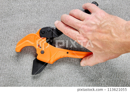 Ratcheting PVC pipe cutter, tube cutting tool for one-handed use, on gray background. Ratcheting PVC pipe cutter, tube cutting tool for one-handed use, on gray background. 113621055