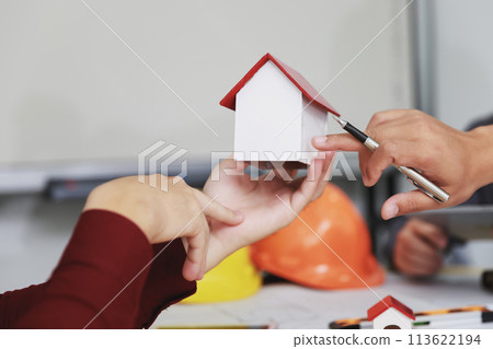 House model on hand over confident team of architects working together in a office. Business, architecture, building construction and real estate concept. 113622194