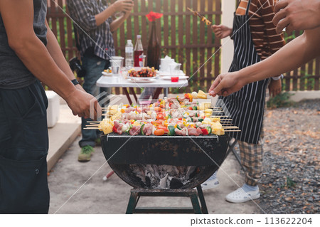Men grilling pork and barbecue in dinner party. Food, people and family time concept. Men grilling pork and barbecue in dinner party. Food, people and family time concept. 113622204