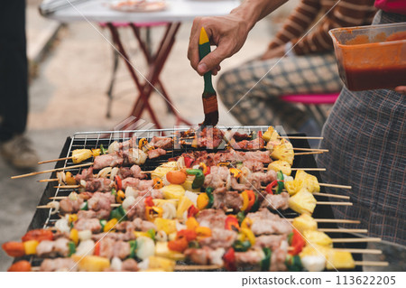A man grilling pork and barbecue in dinner party. Food, people and family time concept. 113622205