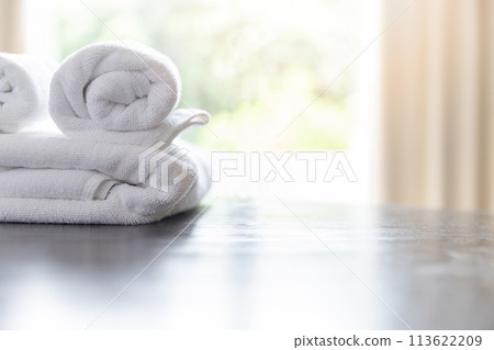 Roll up of white towels on table with copy space on blurred room background. For product display montage. Roll up of white towels on table with copy space on blurred room background. For product display montage. 113622209