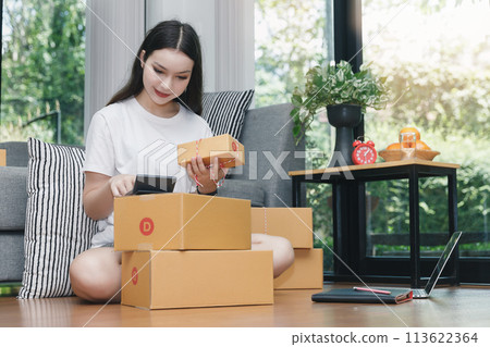 A woman using a calculator to calculate the price of items. Successful entrepreneur business woman with online sales and Parcel shipping in her home office. 113622364