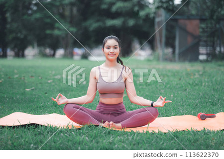 Asian woman practicing yoga in Root Bond, Mula Bandha pose on the mat in outdoor park. 113622370