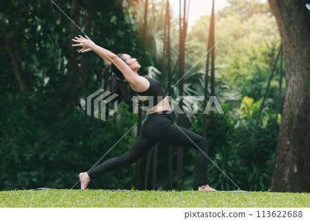 Asian woman practicing yoga in High Lunge, Crescent pose on the mat in outdoor park. Asian woman practicing yoga in High Lunge, Crescent pose on the mat in outdoor park. 113622688