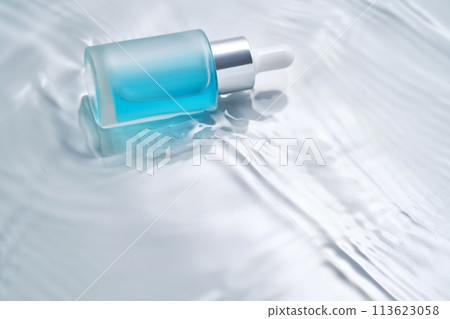 Bottles of cosmetics with a dropper in water on a blue background. 113623058
