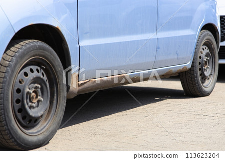 A light vehicle with severe rust on the body due to salt damage from snow melting agents in snowy regions 113623204