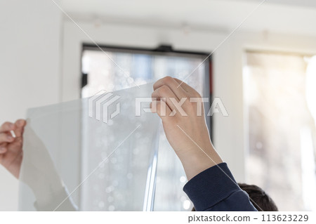 Installation of tinted film, foil in hands. Ultraviolet and energy afficiency concept. 113623229