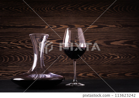 Decanter and glass with red wine on wooden rustic background Decanter and glass with red wine on wooden rustic background 113623242
