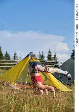 Woman making yoga in mountains. Flexible, sporty woman doing yoga, training, meditating. Slim, young female standing on head, stretching, exercising outdoors. Concept of yoga doing. Woman making yoga in mountains. Flexible, sporty woman doing yoga, training, meditating. Slim, young female standing on head, stretching, exercising outdoors. Concept of yoga doing. 113623917