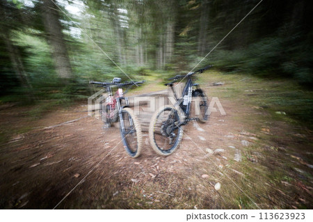 Two modern electric mountain bikes leaning on the fence (no people). Motion blur 113623923