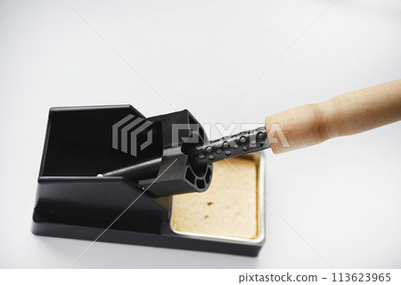 Soldering iron with a wooden handle in the holder. A soldering iron stand. Soldering iron with a wooden handle in the holder. A soldering iron stand. 113623965