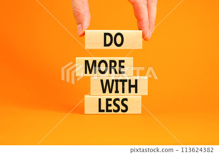 Do more with less symbol. Concept word Do more with less on beautiful wooden block. Beautiful orange table orange background. Businessman hand. Business do more with less concept. Copy space. Do more with less symbol. Concept word Do more with less on beautiful wooden block. Beautiful orange table orange background. Businessman hand. Business do more with less concept. Copy space. 113624382
