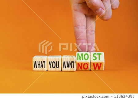 What you want now or most symbol. Concept word What you want now or most on cubes. Beautiful orange background. Psychologist hand. Psychological what you want now or most concept. Copy space. 113624395