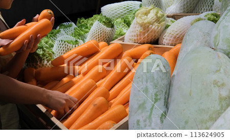 Young mother with little daughter buying carrots at grocery. Healthy vegetarian food concept 113624905