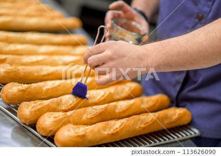 Unrecognizable man baker baking baguettes in bakehouse 113626090