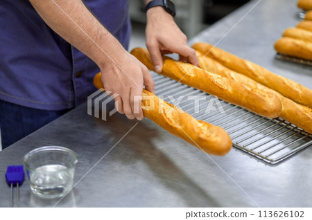 Unrecognizable man baker baking baguettes in bakehouse 113626102