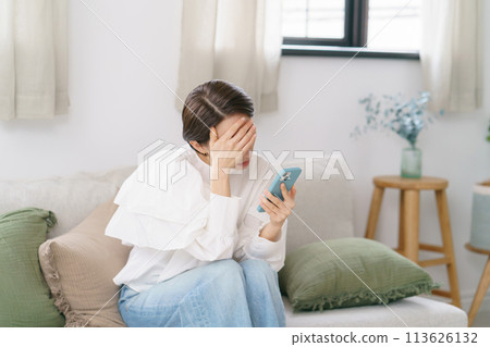 中年婦女一邊看著智慧型手機一邊擔心 113626132