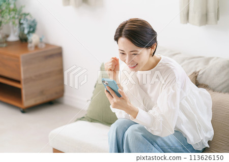 一位 30 多歲的女性很高興地看著她的智慧型手機 113626150