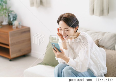 A woman in her 30s is happy to see her smartphone 113626152