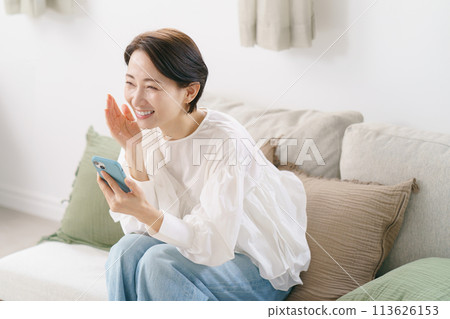 一位 30 多歲的女性很高興地看著她的智慧型手機 113626153