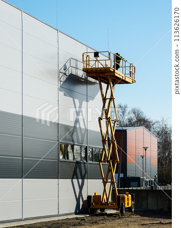 High elevated yellow self propelled scissor lift platform with worker for building wall inspection High elevated yellow self propelled scissor lift platform with worker for building wall inspection 113626170