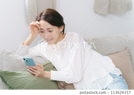 Middle-aged woman relaxing while looking at her smartphone 113626357