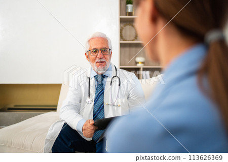 Senior man doctor examining young woman in doctor office clinic or at home. Girl patient and doctor have consultation in hospital room. Medicine healthcare medical checkup. Visit to doctor Senior man doctor examining young woman in doctor office clinic or at home. Girl patient and doctor have consultation in hospital room. Medicine healthcare medical checkup. Visit to doctor 113626369