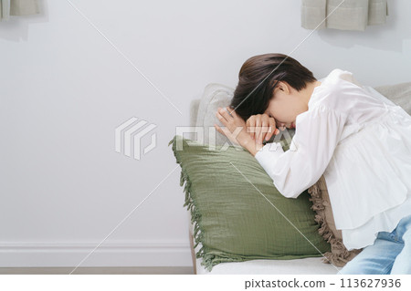 A woman collapses onto the sofa 113627936