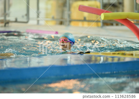 A child in a silicone cap and glasses learns to swim in the pool A child in a silicone cap and glasses learns to swim in the pool 113628586