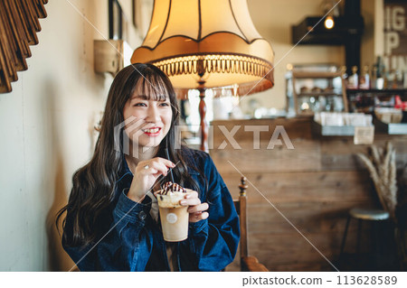 A woman drinking at a cafe A woman drinking at a cafe 113628589